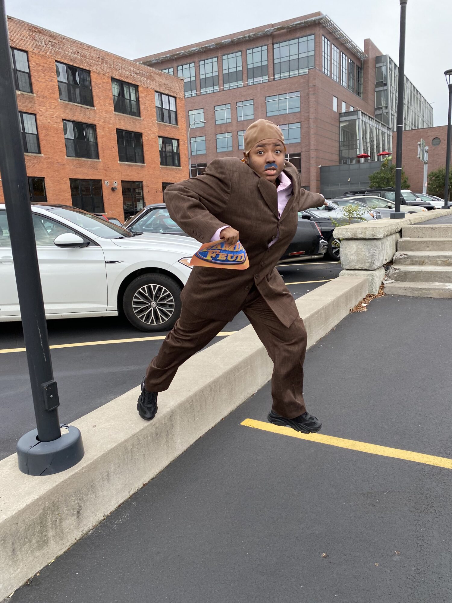 Raven, dressed as Steve Harvey, jumps through a parking lot