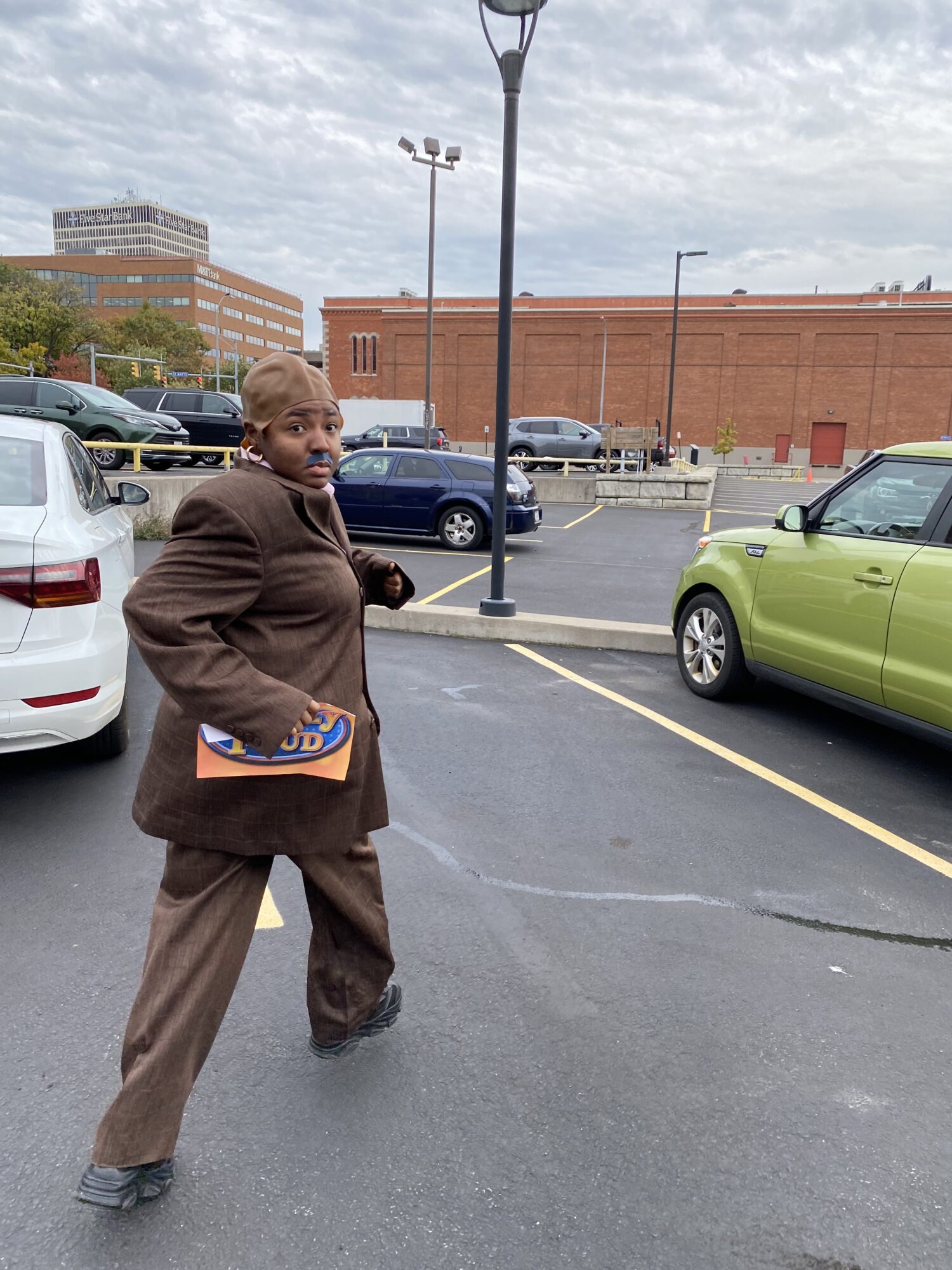 Raven, dressed as Steve Harvey, jumps through a parking lot. It looks like she is running from something... or someone